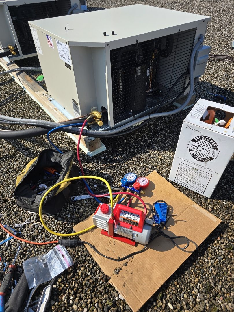Vacuum pump and manifold gauges during rooftop refrigerant service